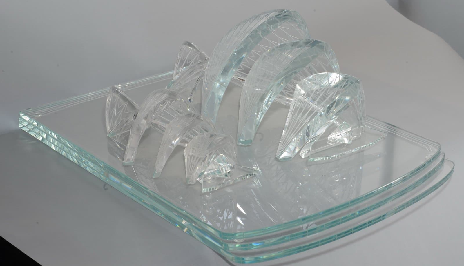 Overlapping clear architectural arches and small building forms on a rounded transparent platform