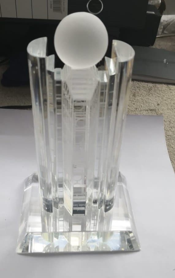 Clear tower miniature with closely spaced vertical columns and a large sphere above a stepped base
