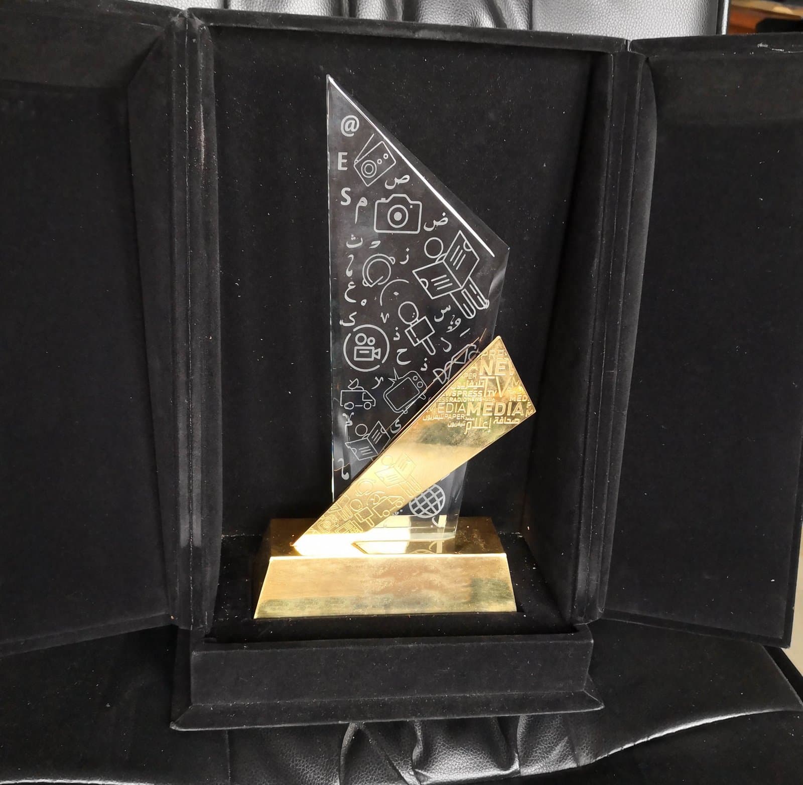 Patterned triangular award panel crossed by a gold-toned diagonal on a dark base in a black case