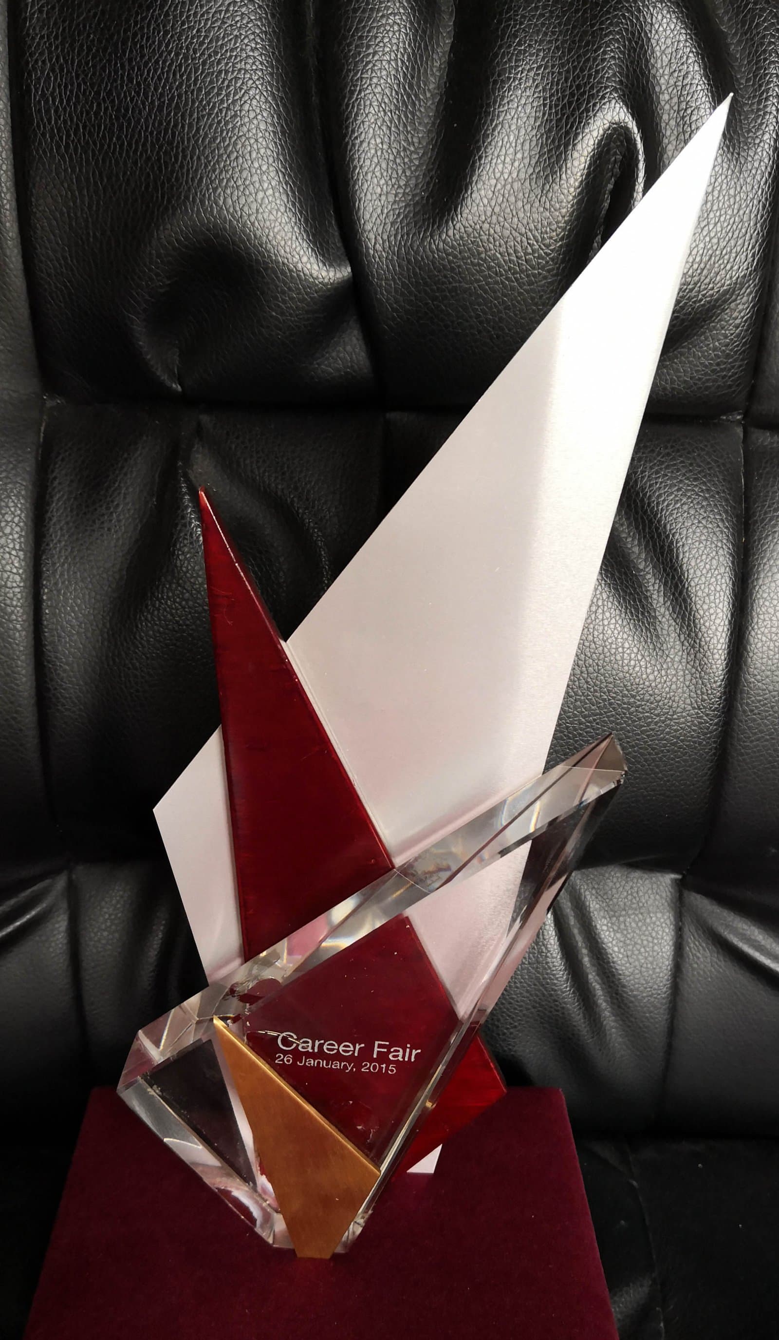 Tall pointed clear award with red sections and angular gold-toned accents near its base
