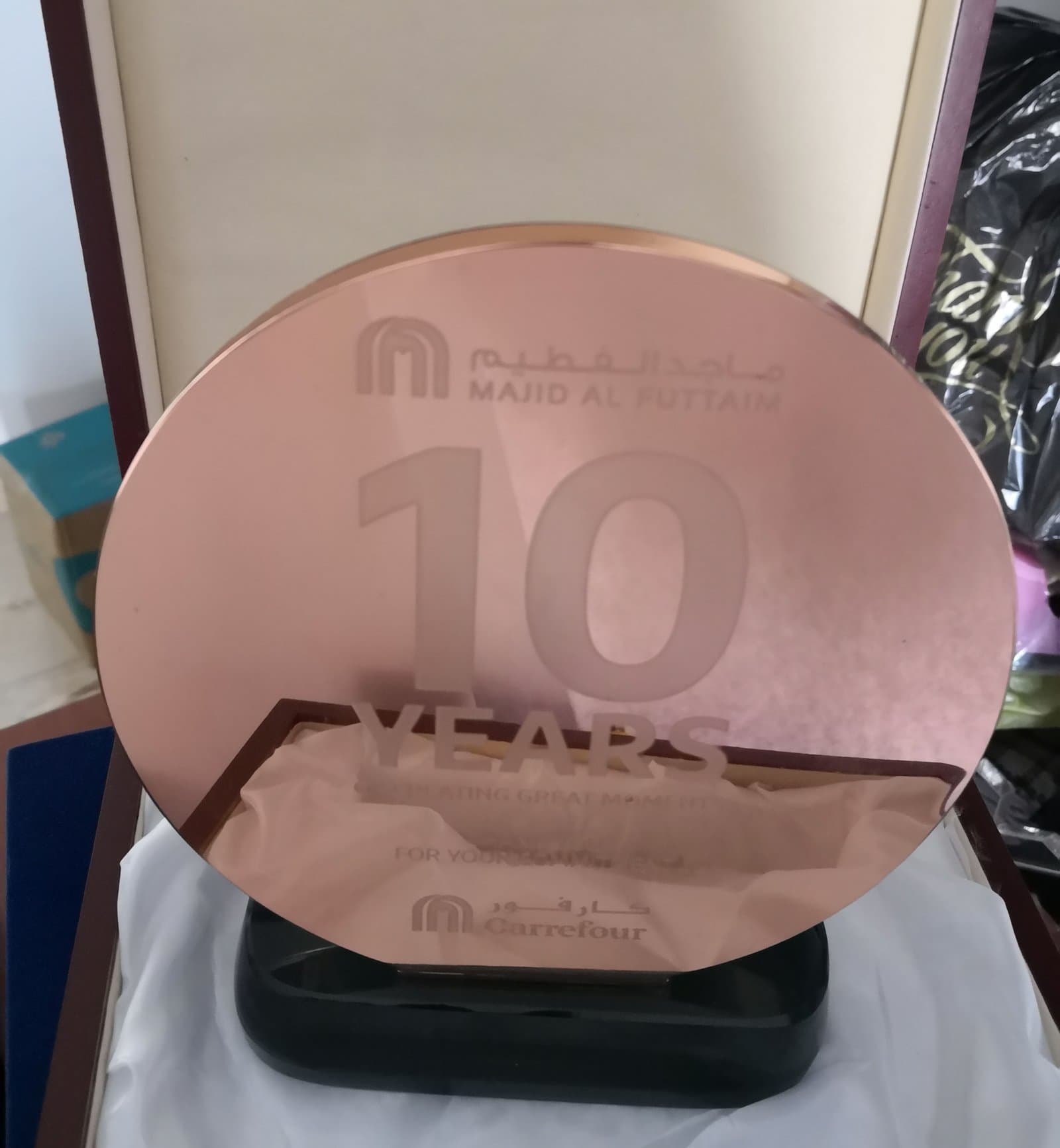 Round warm-toned award bearing a large 10-year anniversary message on a dark base