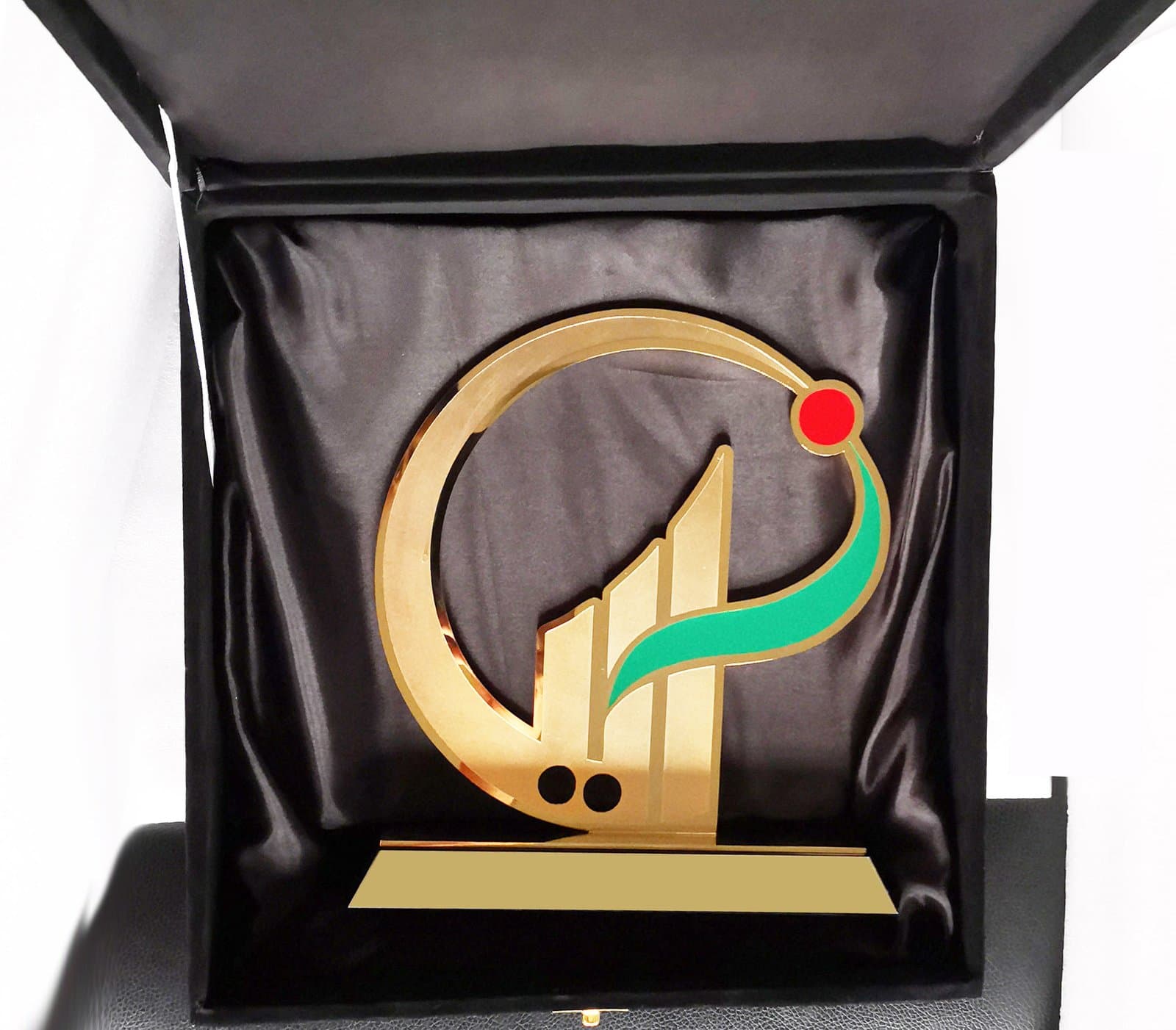 Open gold-toned ring around a green and red calligraphic motif in a dark presentation case