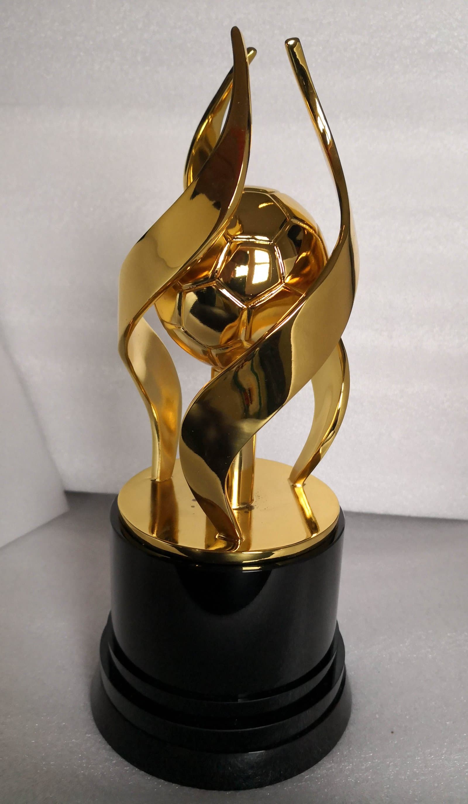 Alternate view of a gold-toned sports trophy with rising curved tips and a round centre