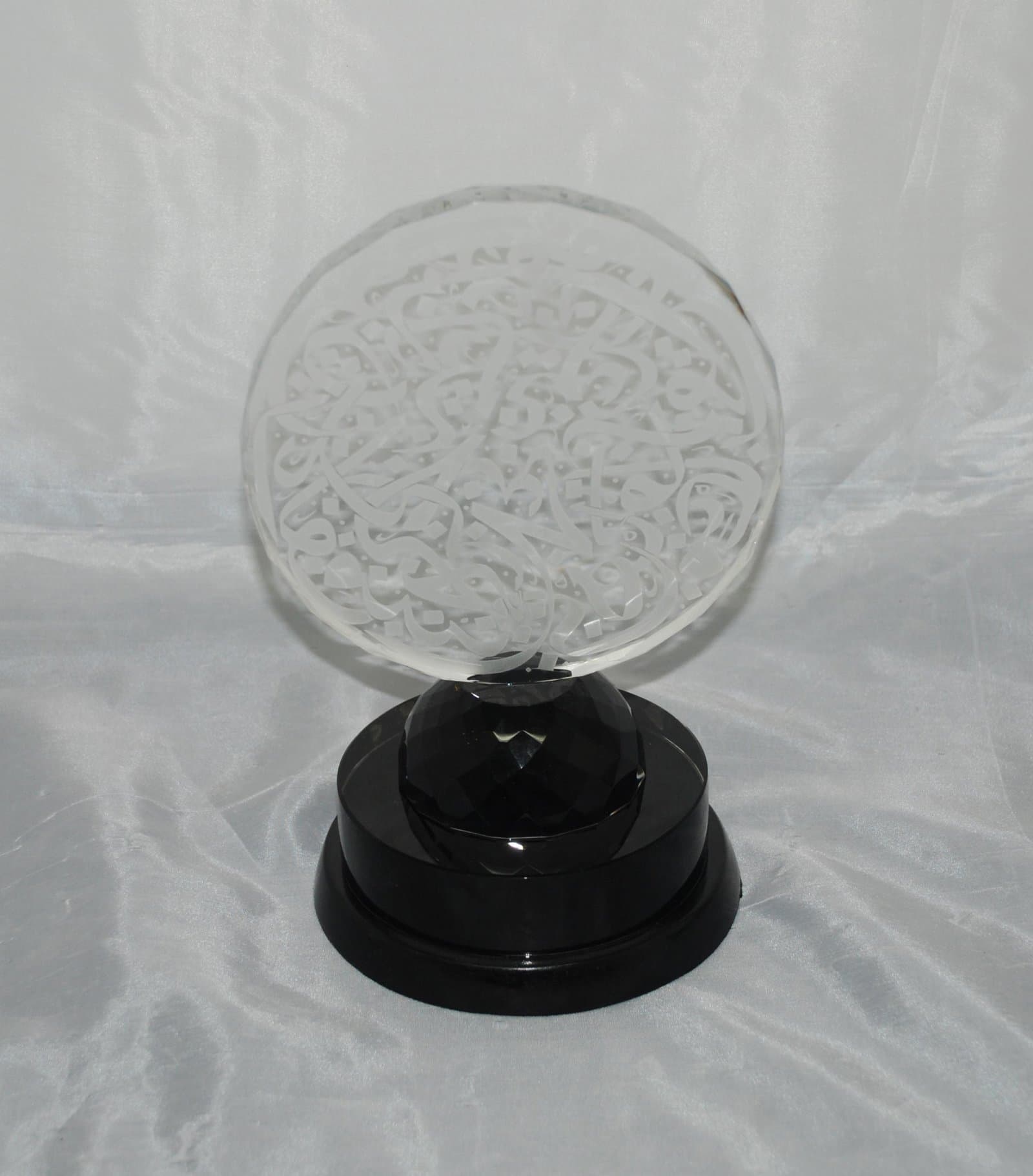 Round clear engraved plaque on a short support above a tiered circular dark base