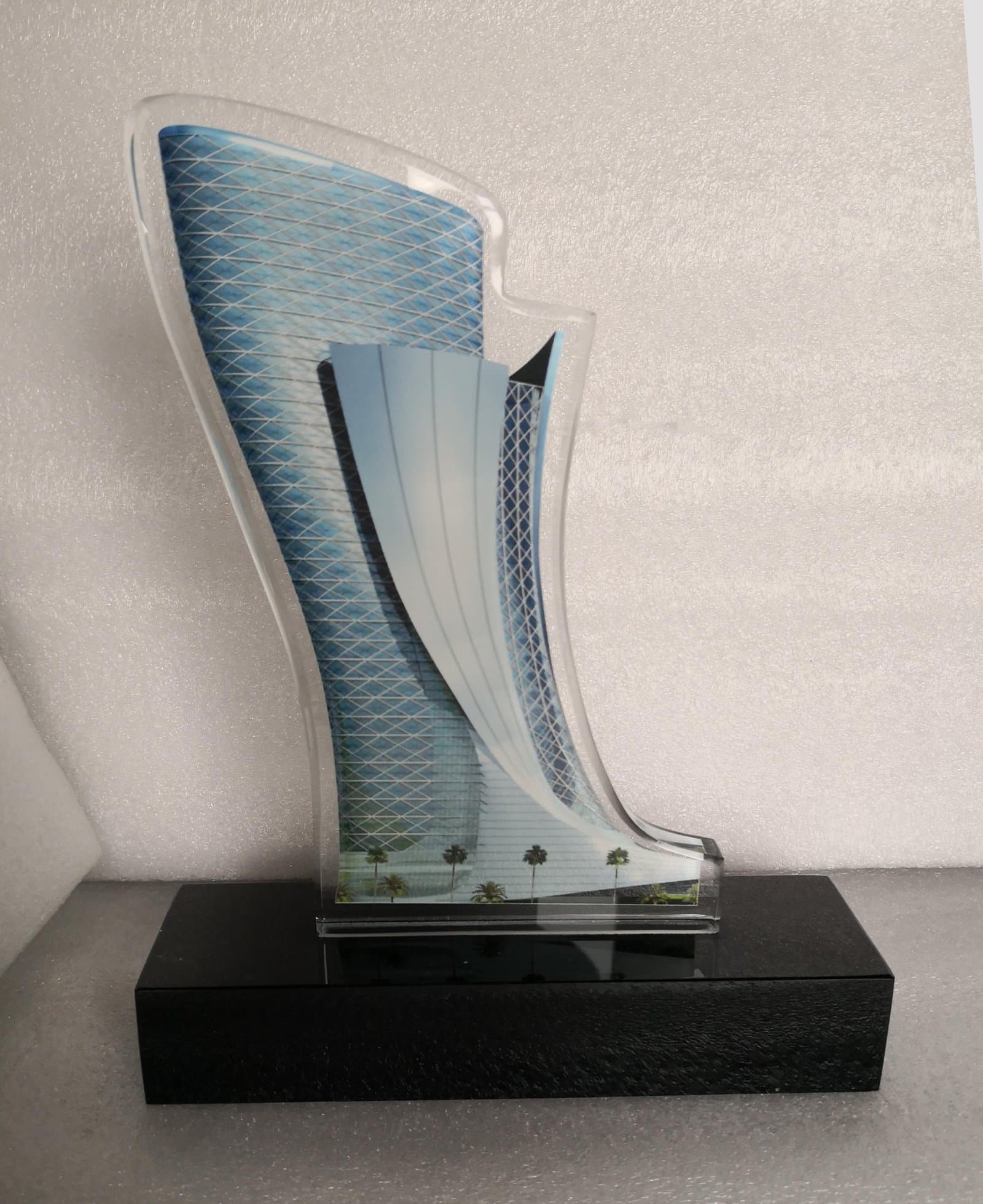Broad patterned leaning tower panel beside a narrower curved form on a black rectangular base
