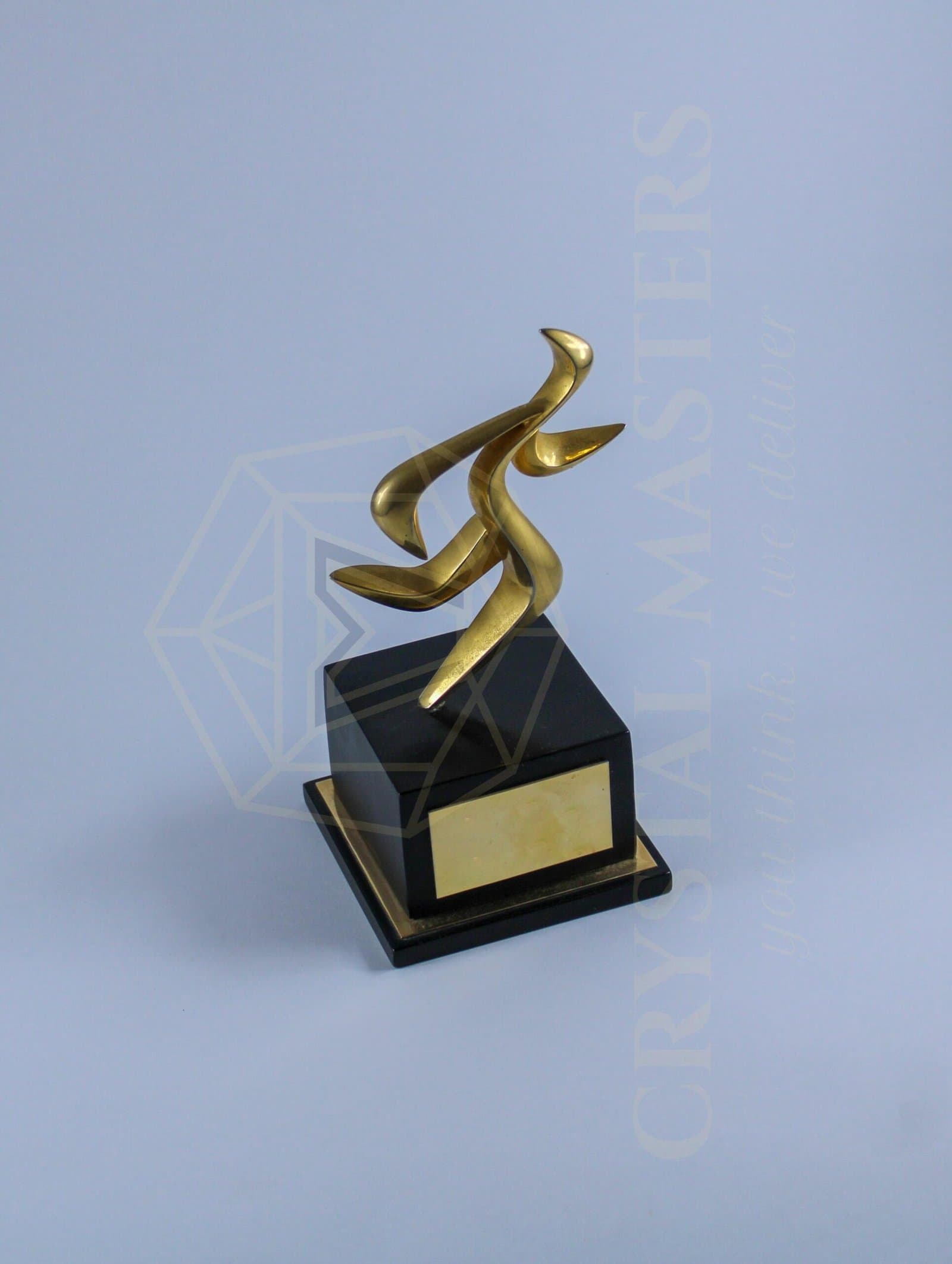 Upright gold-toned calligraphic metal form on a black pedestal with a framed front panel