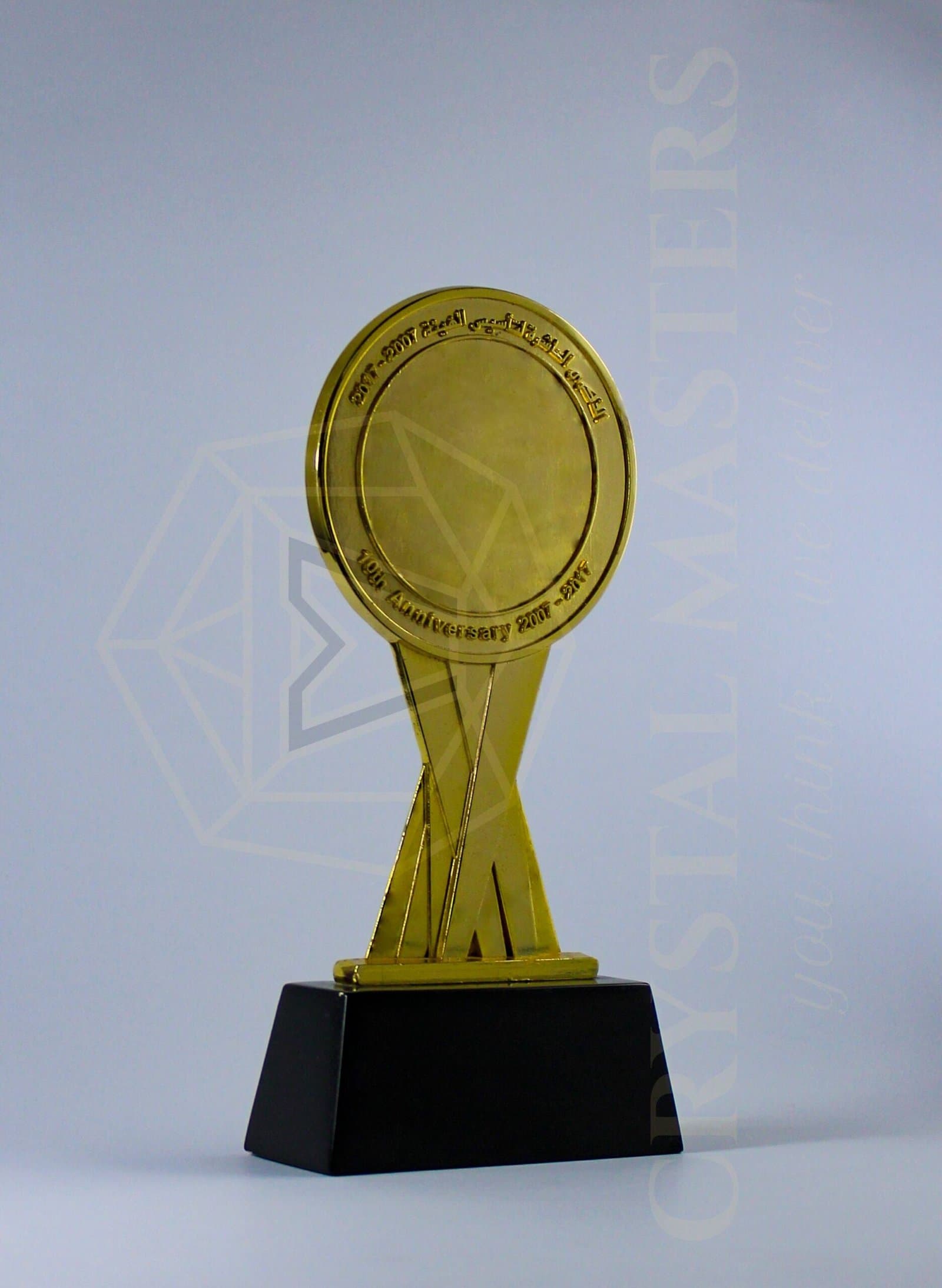 Gold-toned circular medallion on tapered uprights above a dark rectangular pedestal