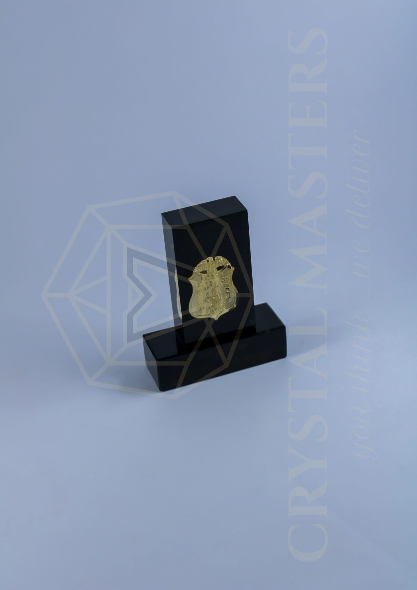 Black upright plaque with a centred gold-toned emblem and a matching dark base