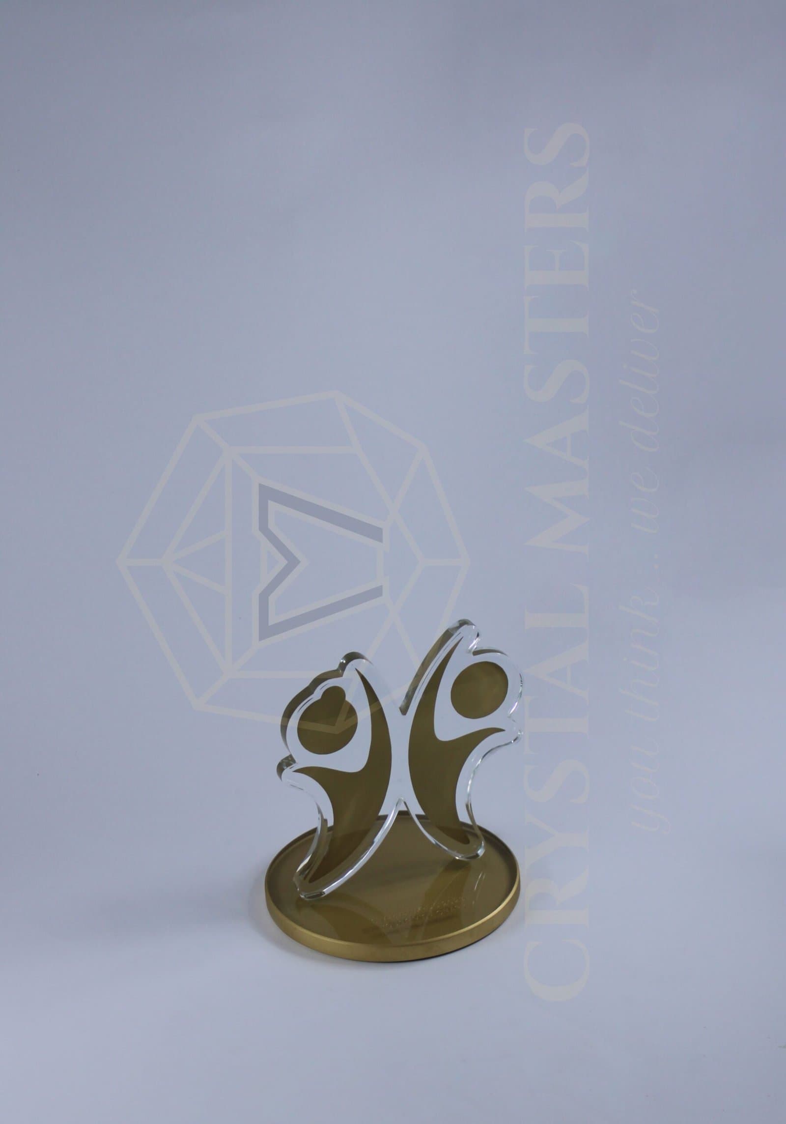 Two gold-toned curved figure-like shapes with round heads and pale edges on a circular base