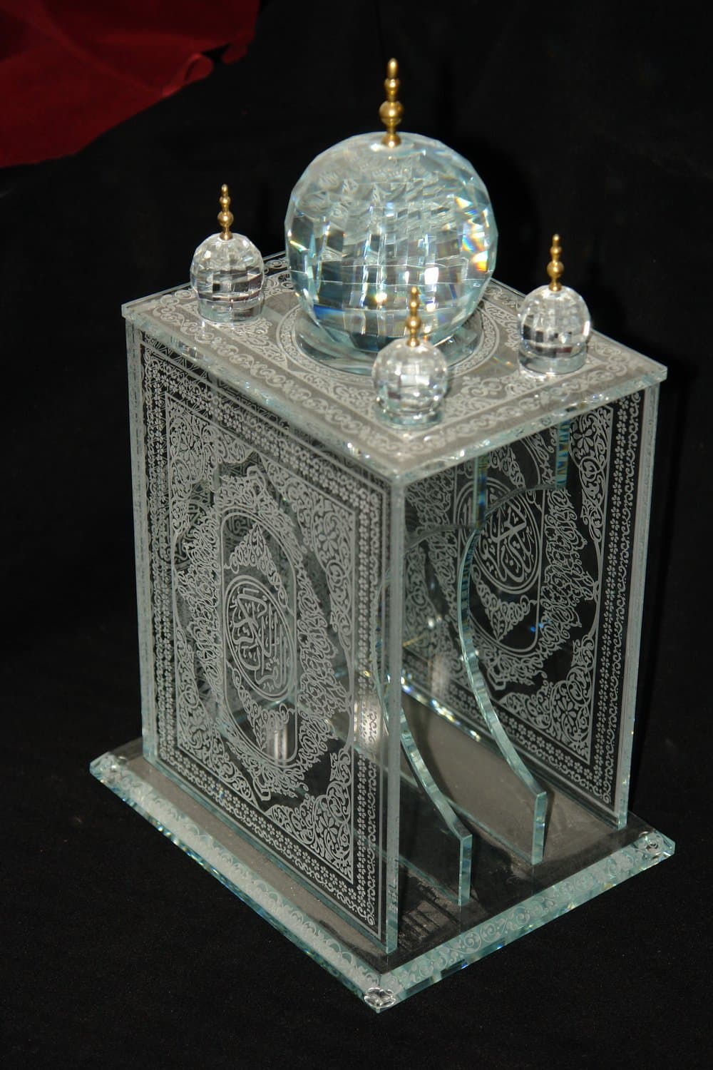 Ornamented rectangular Islamic display with a clear rounded dome, corner details and a small finial